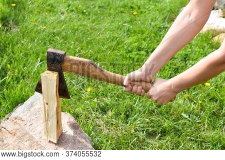 Woman Chopping A Log With An Ax In The Garden. Rural Life In The Summer. Chopping Firewood In The Fr