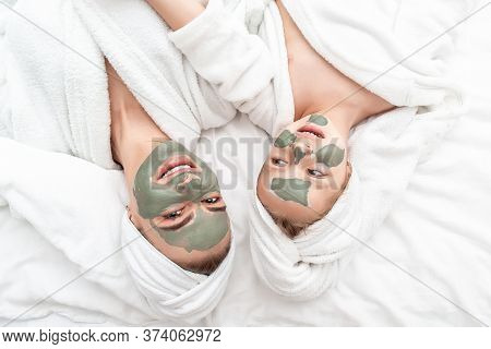 Positive Mother And Daughter After Shower Doing Face Mask. Bathtime Concept.