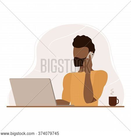 Male Office Worker. Swarthy Man Uses Laptop, Speaks On Cell Phone, Sitting At Table. Personal Assist