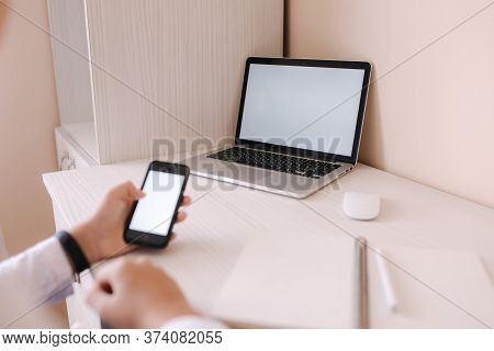 Schoolboy Study At Desk In His Room. Boy Use Laptop And Smartphone To Writing In Notebook. Books And