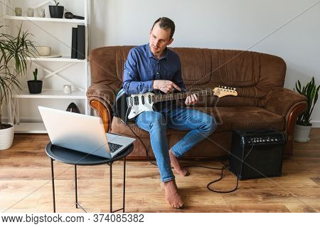 Online Studying, Webinars. A Young Man Is Shows How To Play Electric Guitar To Laptop Webcam. Online