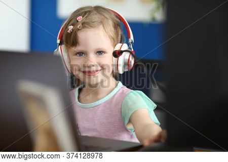 Portrait Of Smiling Girl Looking At Camera With Gladness And Calmness. Happy Baby Playing Computer G