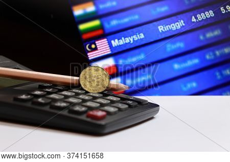 Fifty Cents Coin Of Malaysia And Pencil On The Calculator With Digital Board Of Currency Exchange Mo