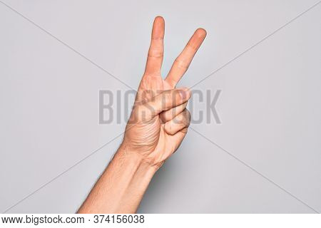 Hand of caucasian young man showing fingers over isolated white background counting number 2 showing two fingers, gesturing victory and winner symbol