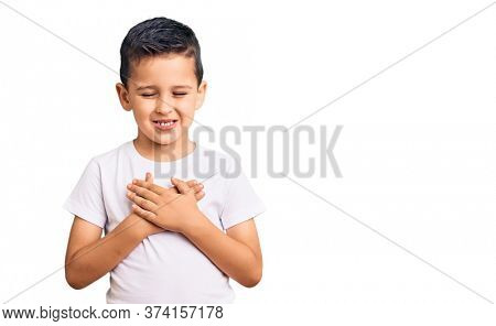 Little cute boy kid wearing casual white tshirt smiling with hands on chest with closed eyes and grateful gesture on face. health concept. 
