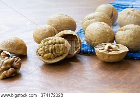 Whole Walnuts And Walnut Kernel Halves Without Shell On A Dark Wooden Table And Checkered Towel, Clo