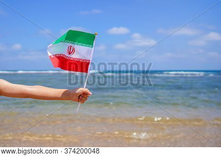 Hands Of Kid Girl Holding Iran Flag Against The Sea Horizon. 21th Of February Independence Day Of Ir