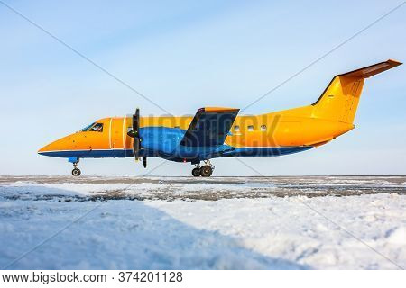 Orange Turboprop Aircraft On The Winter Airport Apron