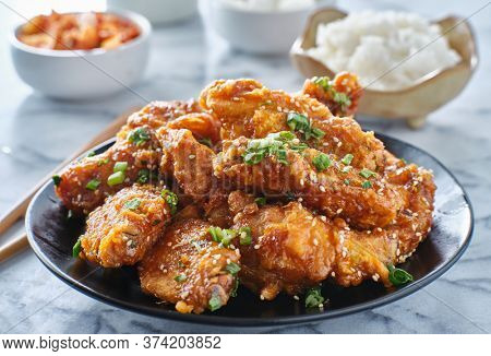 crispy fried korean chicken wings in galbi sauce with pickled radish, kimchi, and rice side dishes