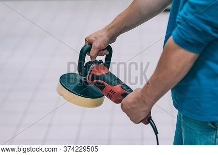 A Man Holds A Polishing Machine In His Hand. A Buyer In A Hardware Store Selects A Product.