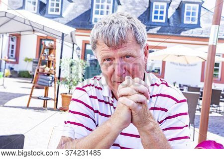 Handsome Mature Man Sitting Outside In A Beergarden And Enjoys Life
