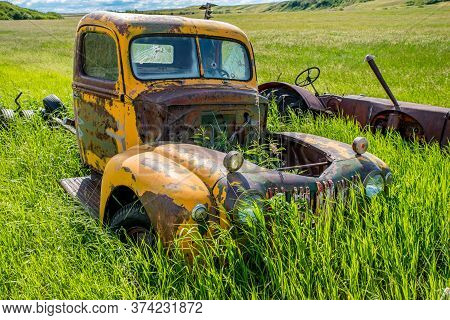 Wymark, Sk/canada- June 28, 2020:  Abandoned Vintage Yellow Ford Truck And Massey Harris Tractor In 