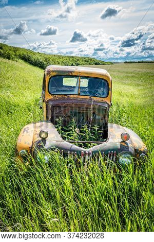 Wymark, Sk/canada- June 28, 2020:  Weeds Growing Up Through The Empty Hood Of An Abandoned Vintage F
