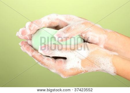 ผู้หญิงมือใน soapsuds บนพื้นหลังสีเขียวอย่างใกล้ชิด