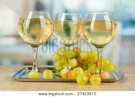 Vino bianco nel vetro su salver sullo sfondo della camera