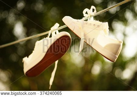 White Sneakers After Washing Are Dried On A Rope In A Summer Garden.