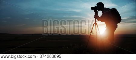 Side Silhouette Of Photographer Taking Pictures Using Dslr Camera And Tripod On Sunset Or Sunrise