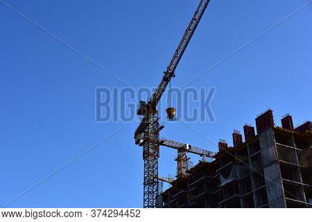 Preparing To Pour A Bucket Of Concrete Into Formwork.tower Crane Lifting Cement Bucket During Constr