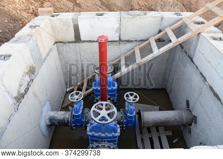 Gate Valves In Valve Pit Of The Underground Piping Networks. Laying Water System Pipeline At Constru