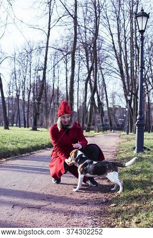 Pretty Young Girl In Redd Coat Playing With Dog Outside In Green Park, Lifestyle People Concept