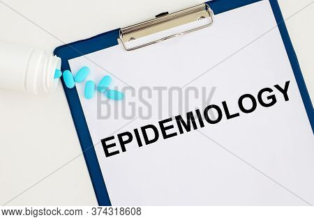 The Word Epidemiology On White Paper Sheet On Blue Board With Scattered Blue Pills. Health Concept