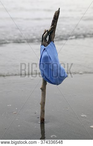 Blue Surgical Mask Like A Flag On The Beach By The Sea