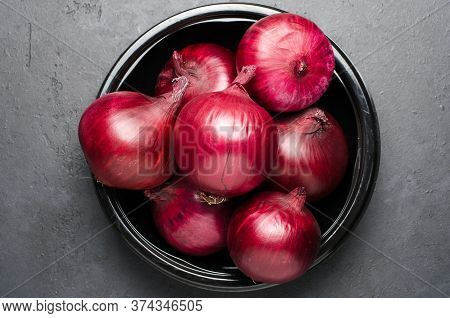 Red Ripe Onion In A Black Plate. Dark Background.