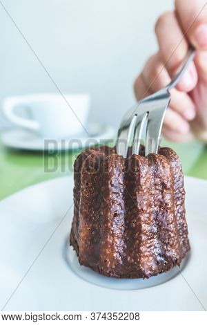 Traveler Woman Hand Holding A Fork And Cutting A Canelé (canele - Caneles De Bordeaux) Traditional F