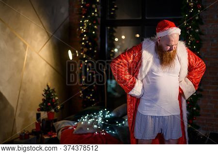 Bad Santa Claus Lonely At Christmas. Aggressive Man In A Suit Of Santa Claus On The Background Of Ne