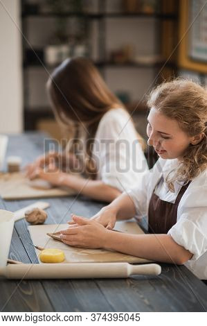 Female Potters Making Clay Pottery At The Table With A Different Wooden Tools. Happy And Smiling Wom