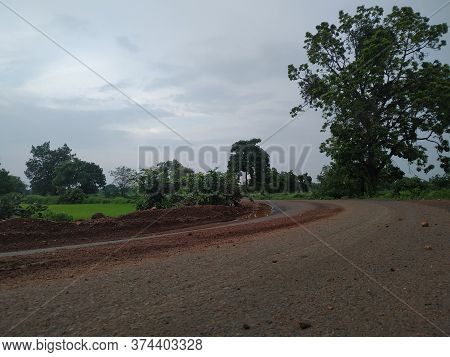 Countryside Road Between Farms Under Cloudy Sky In Monsoon