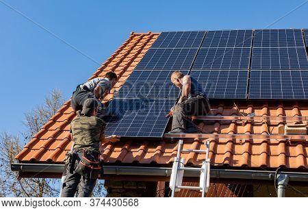 Ochojno, Poland - April 8, 2020: Workers Installing Solar Electric Panels On A House Roof In  Ochojn