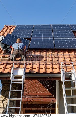 Ochojno, Poland - April 8, 2020: Workers Installing Solar Electric Panels On A House Roof In  Ochojn