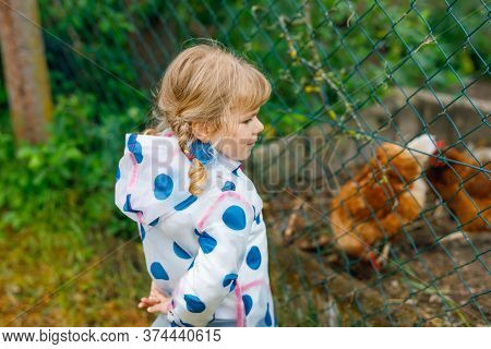 Outdoor Portrait Of Happy Smiling Little Toddler Girl Wearing Rain Jacket On Rainy Cloudy Day Feedin