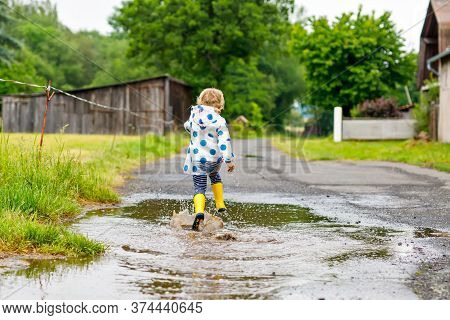 Little Toddler Girl Wearing Yellow Rain Boots, Running And Walking During Sleet On Rainy Cloudy Day.