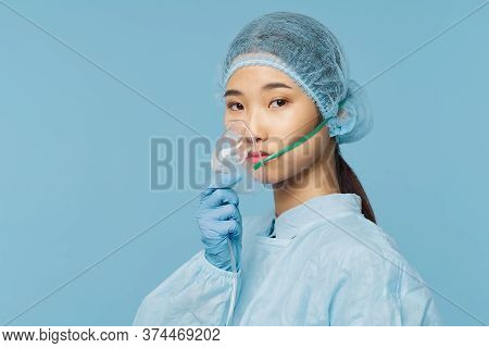 A Woman In A Medical Suit, A Cap On Her Head And An Oxygen Mask