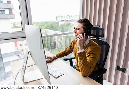 Businessman Making Phone Call Sitting At Desk In Modern Office