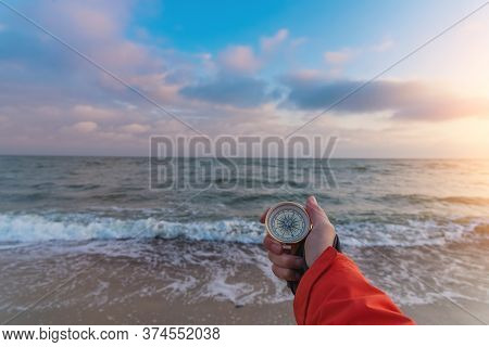 First-person View Of A Female Hand With A Compass On A Background Of A Beautiful Sea Landscape. The 