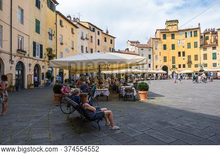 Lucca, Italy - August 14, 2019: Tourists And Locals Visit Ancient Amphitheater Square Or Piazza Dell