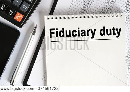 On The Table Lies A Smartphone, A Calculator And A Notebook With The Inscription- Fiduciary Duty. Bu