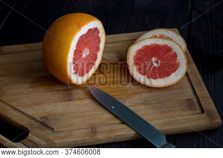Cut The Grapefruit On A Wooden Plate On A Wooden Table