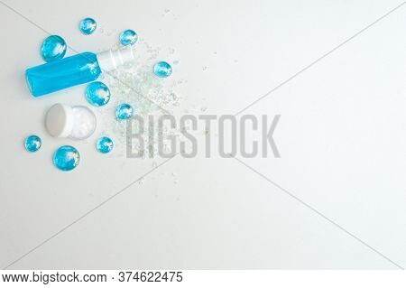 Blue Gel Spray, Drops, Glass, Bath Salt And Moisturizer On A White Background, Top View. Copy Space