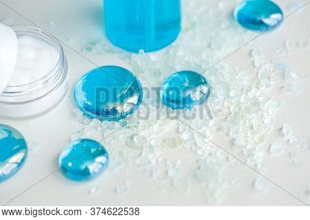 Blue Gel Spray, Drops, Glass, Bath Salt And Moisturizer On A White Background, Top View.
