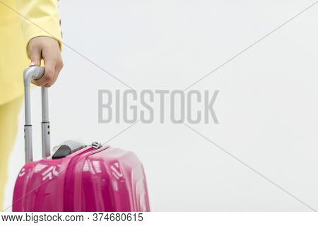 Cropped Shot Of Female Hand Carrying A Pink Suitcase Over White Background With Copyspace.