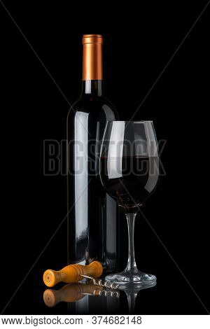 Bottle Of Red Wine Next To A Glass And A Corkscrew Isolated On Black Background