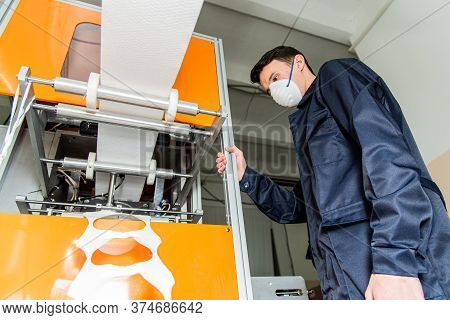 A Man Works At A Machine For The Manufacture Of Medical Masks With Nanofiber. Coronovirus And Covid-