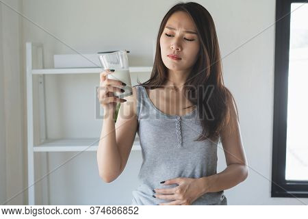 Lactose Intolerance Concept. Woman Holding A Glass Of Milk And Having A Stomachache.
