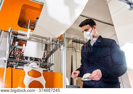 A Man Works At A Machine For The Manufacture Of Medical Masks With Nanofiber. Coronovirus And Covid-