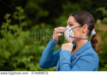 Beautiful Girl Puts A Medical Mask On Her Face On The Nature. Coronavirus And Covid-19 Protection