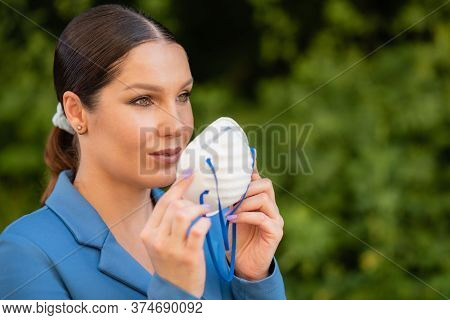Beautiful Girl Puts A Medical Mask On Her Face On The Nature. Coronavirus And Covid-19 Protection